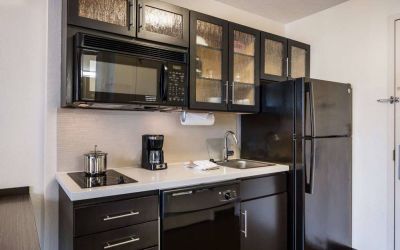 Sonesta Simply Suites Dallas Galleria guest room kitchen, furnished with fridge-freezer, hob, oven, and microwave.