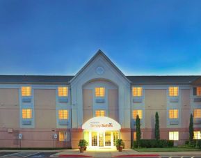 Sonesta Simply Suites Dallas Galleria’s exterior has well-kept greenery, including potted plants, clear signage, and parking spaces.