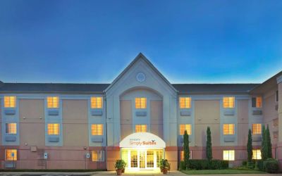 Sonesta Simply Suites Dallas Galleria’s exterior has well-kept greenery, including potted plants, clear signage, and parking spaces.