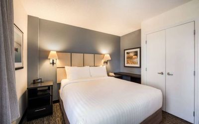 Sonesta Simply Suites Pittsburgh Airport double bed guest room, with art on the walls and bedside lighting.