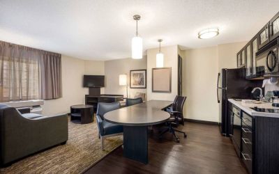 Sonesta Simply Suites Pittsburgh Airport guest room living area, with table and chairs between the kitchen and sofa/TV.