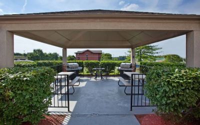 Sonesta Simply Suites Pittsburgh Airport’s gazebo features seating and tables outdoors and under cover, with two barbecues and a surrounding hedge.