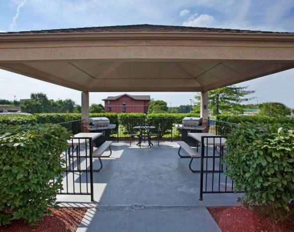 Sonesta Simply Suites Pittsburgh Airport’s gazebo features seating and tables outdoors and under cover, with two barbecues and a surrounding hedge.