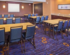 Meeting room in Sonesta Select Tinton Falls Eatontown, with tables arranged in a classroom format facing a projector screen.