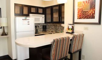 Guest room kitchen in Sonesta ES Suites Portland Vancouver 41st Street, featuring fridge-freezer, microwave, breakfast bar and two stools.