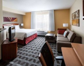 Sonesta Simply Suites Seattle Renton double bed guest room lounge, including sofa, TV, chair, and window.