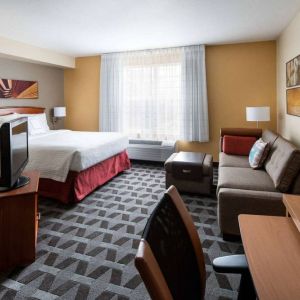 Sonesta Simply Suites Seattle Renton double bed guest room lounge, including sofa, TV, chair, and window.