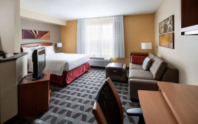 Sonesta Simply Suites Seattle Renton double bed guest room lounge, including sofa, TV, chair, and window.