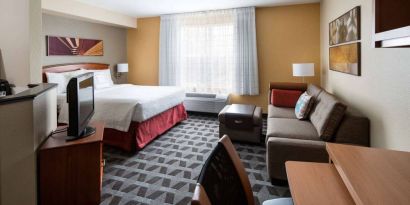 Sonesta Simply Suites Seattle Renton double bed guest room lounge, including sofa, TV, chair, and window.