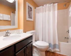 Sonesta Simply Suites Seattle Renton guest bathroom, furnished with bath and shower, lavatory, and mirror and sink.