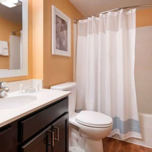 Sonesta Simply Suites Seattle Renton guest bathroom, furnished with bath and shower, lavatory, and mirror and sink.