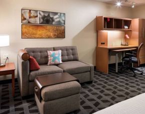 Guest room workspace in Sonesta Simply Suites Seattle Renton, featuring desk, lamp, and chair, with nearby sofa.