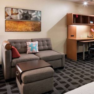 Guest room workspace in Sonesta Simply Suites Seattle Renton, featuring desk, lamp, and chair, with nearby sofa.