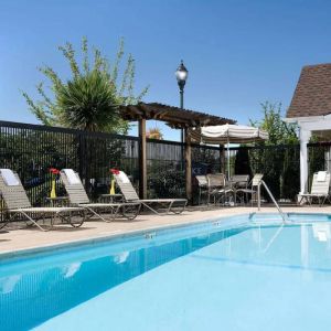 Sonesta Simply Suites Seattle Renton’s outdoor pool is fenced off and has both sun loungers and chairs by the side.