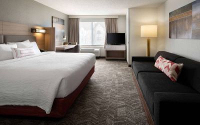Sonesta Select Seattle Renton double bed guest room, with sofa, workspace desk and chair, TV, and large window.