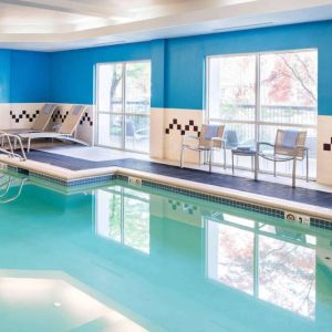 The indoor pool at Sonesta Select Seattle Renton features large windows, and has both chairs and loungers by the side.