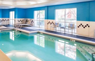 The indoor pool at Sonesta Select Seattle Renton features large windows, and has both chairs and loungers by the side.