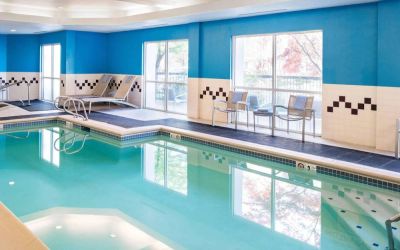 The indoor pool at Sonesta Select Seattle Renton features large windows, and has both chairs and loungers by the side.