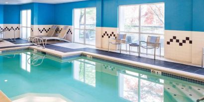 The indoor pool at Sonesta Select Seattle Renton features large windows, and has both chairs and loungers by the side.
