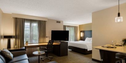 Sonesta ES Suites Parsippany Morris Plains double bed guest room, including TV and sofa, with a workspace desk and chair.