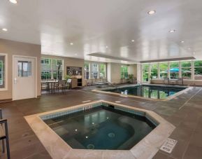 Sonesta ES Suites Parsippany Morris Plains’ indoor pool has a hot tub nearby, chairs and sun loungers nearby, and large windows.