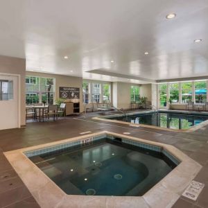 Sonesta ES Suites Parsippany Morris Plains’ indoor pool has a hot tub nearby, chairs and sun loungers nearby, and large windows.