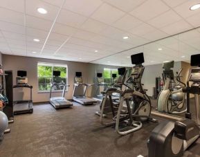 The fitness center in Sonesta ES Suites Parsippany Morris Plains has windows with green views and a wide range of exercise machines.