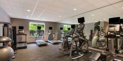 The fitness center in Sonesta ES Suites Parsippany Morris Plains has windows with green views and a wide range of exercise machines.
