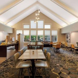 The hotel’s breakfast area is spacious and has large windows, with tables varying from two seats to eight, and art on the wall.