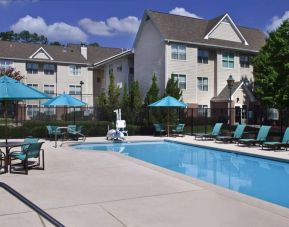 The outdoor pool of Sonesta ES Suites Birmingham Homewood is equipped with a lift, and both sun loungers and shaded tables/chairs are in the vicinity.