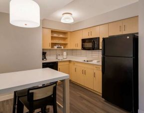 Sonesta ES Suites Andover Boston guest room kitchen, featuring oven, hob, microwave, fridge-freezer, and a kitchen table with two stools.