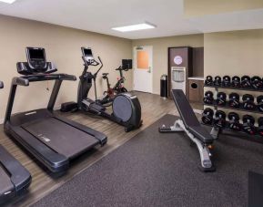 The fitness center in Sonesta ES Suites Andover Boston is equipped with rows of free weights, a bench, and a variety of exercise machines.