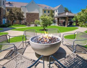 Sonesta ES Suites Andover Boston’s fire-pit is located amid pleasant greenery and surrounded by chairs, with the gazebo and barbecue facilities nearby.