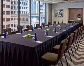 Sonesta Philadelphia Rittenhouse Square meeting room, featuring long table with space for over a dozen attendees, city views through the large windows, and art on the wall.