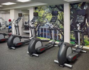 The fitness center in Royal Sonesta New Orleans is equipped with an assortment of exercise machines, and large images of greenery on the walls.