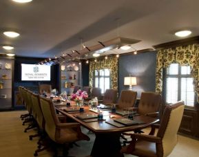 Meeting room in Royal Sonesta New Orleans, furnished with long wooden table, 14 swivel chairs, a widescreen TV, and two windows.