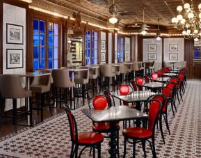 Guests can dine at the hotel restaurant, which has a mosaic-style floor, small tables, and a mix of regular and tall stool seating.