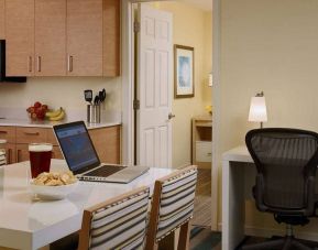 Guest room workspace in Sonesta ES Suites Atlanta - Perimeter Center North, featuring desk, chair, and lamp, next to the kitchen area.