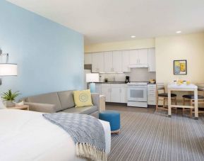 Double bed guest room in Sonesta ES Suites New Orleans, furnished with sofa and TV, plus kitchen area and dining table.