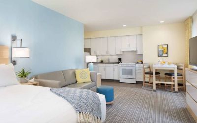 Double bed guest room in Sonesta ES Suites New Orleans, furnished with sofa and TV, plus kitchen area and dining table.