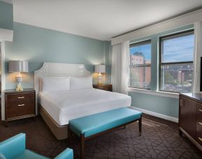 Double bed guest room in The Chase Park Plaza Royal Sonesta St. Louis, featuring armchair, windows, and TV.