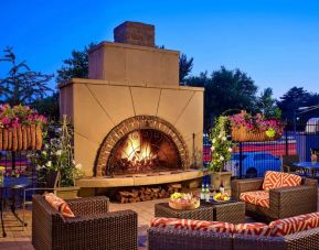 The outdoor fireplace at The Chase Park Plaza Royal Sonesta St. Louis has comfortable sofa and armchair seating nearby, in addition to coffee tables and beautiful flowers.