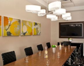 Sonesta Atlanta Airport South meeting room, furnished with long wooden table surrounded by swivel chairs, and art and a widescreen TV on the walls.