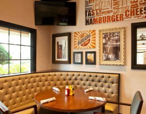 The Burger Place is Sonesta Atlanta Airport South’s on-site restaurant, and includes burger-related art on the wall alongside a widescreen TV, and large windows.