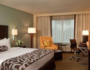 Double bed guest room in Sonesta Atlanta Airport North, featuring TV, window, armchair, and workspace desk and chair.