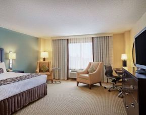 Sonesta Atlanta Airport North double bed guest room, including armchairs, window, and a television.
