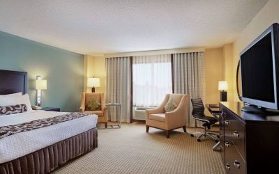 Sonesta Atlanta Airport North double bed guest room, including armchairs, window, and a television.