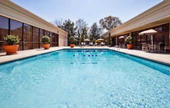 The hotel’s outdoor pool has potted plants by the side, in addition to shaded tables and chairs.