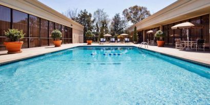 The hotel’s outdoor pool has potted plants by the side, in addition to shaded tables and chairs.