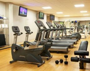 The fitness center at Sonesta Atlanta Airport North includes plenty of towels, free weights, and various types of exercise machines, plus multiple wall-mounted TVs.